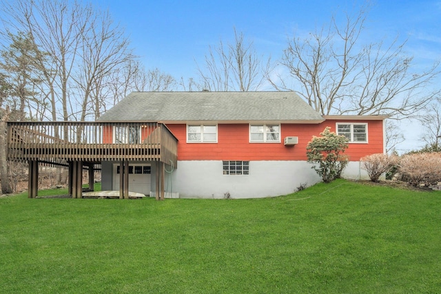 rear view of house with roof with shingles, a lawn, a wall unit AC, and a wooden deck