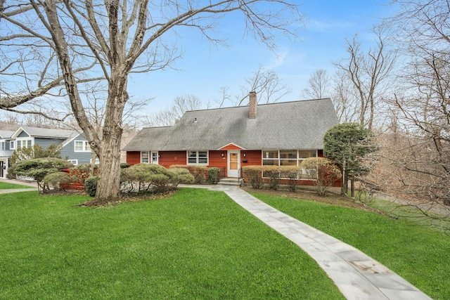 view of front of house with roof with shingles, a chimney, and a front yard