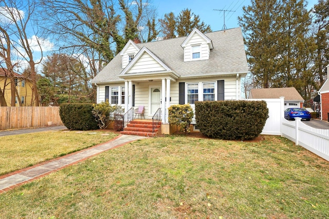 cape cod house featuring a front lawn, roof with shingles, and fence