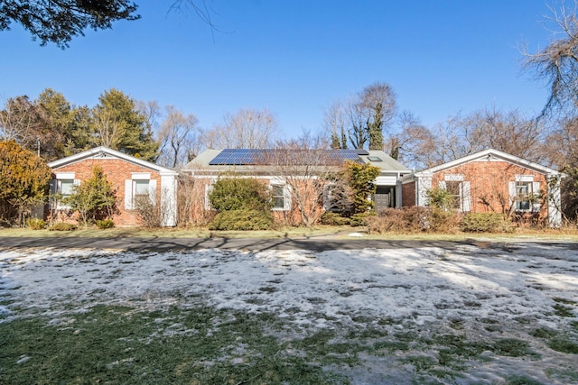 ranch-style home featuring solar panels and brick siding