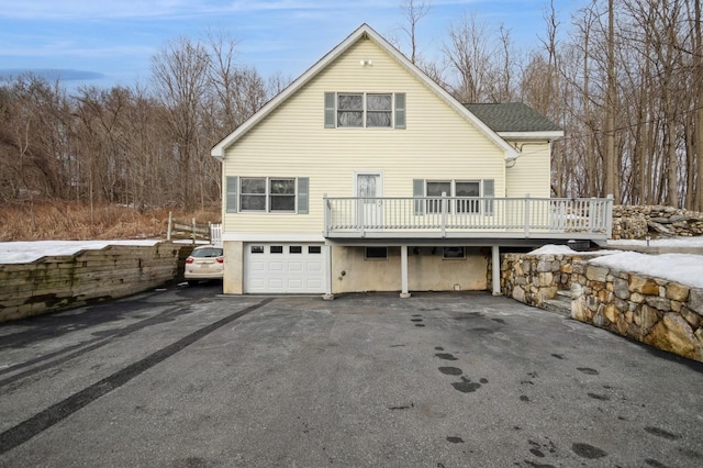 exterior space with aphalt driveway, a wooden deck, and an attached garage