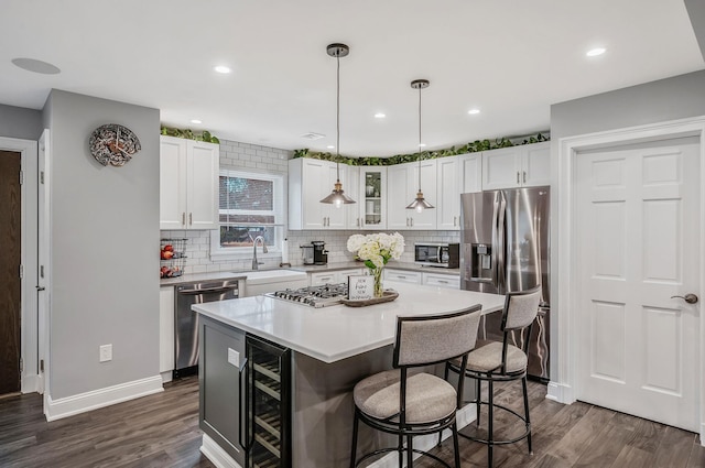 kitchen with beverage cooler, glass insert cabinets, stainless steel appliances, white cabinetry, and a sink