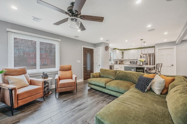 living room with recessed lighting, visible vents, baseboards, and wood finished floors