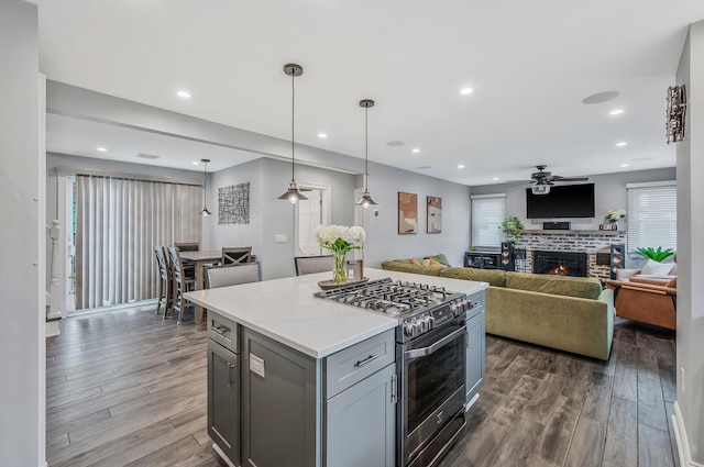 kitchen with dark wood-style flooring, recessed lighting, gray cabinets, gas stove, and a lit fireplace