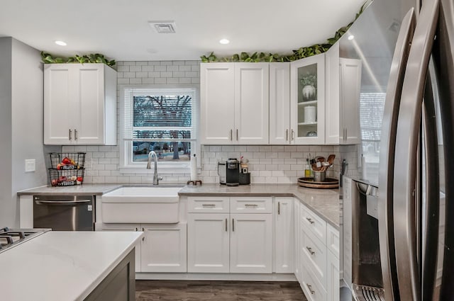 kitchen featuring freestanding refrigerator, white cabinetry, a sink, and dishwashing machine