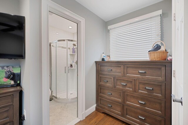 full bath featuring a stall shower, baseboards, and wood finished floors