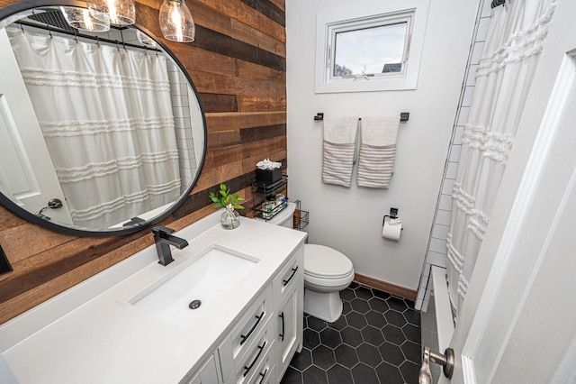 full bathroom featuring wooden walls, baseboards, toilet, tile patterned flooring, and vanity