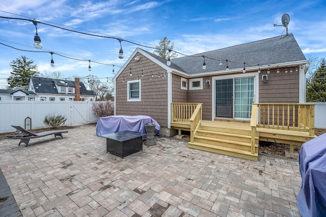 rear view of property featuring a patio, roof with shingles, a gate, fence, and a deck