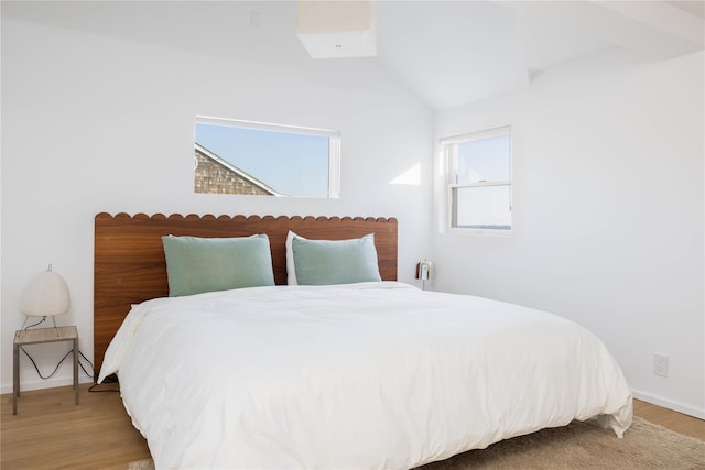 bedroom with lofted ceiling, light wood finished floors, and baseboards