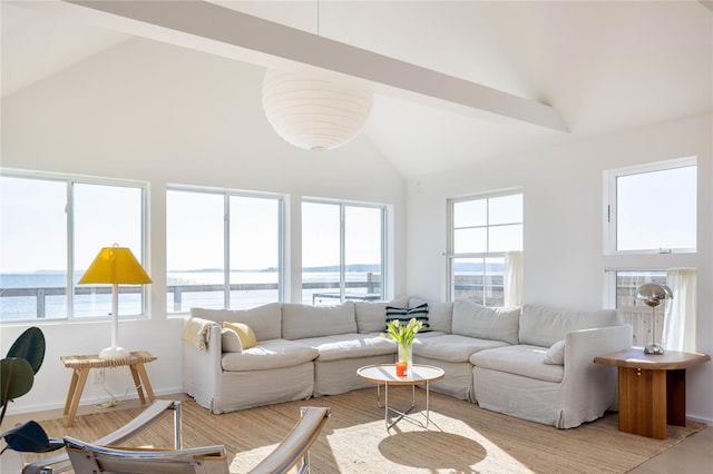 living area with high vaulted ceiling, a water view, and baseboards