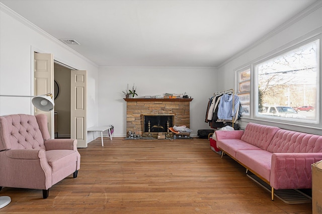 living area featuring light wood-style flooring, a fireplace, visible vents, and crown molding