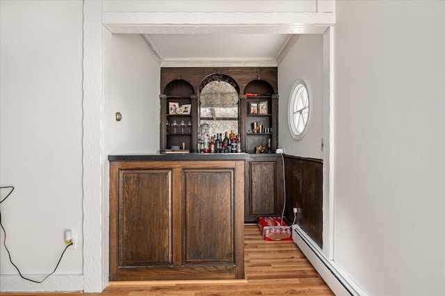 bar with a bar, light wood-style flooring, a baseboard heating unit, and ornamental molding