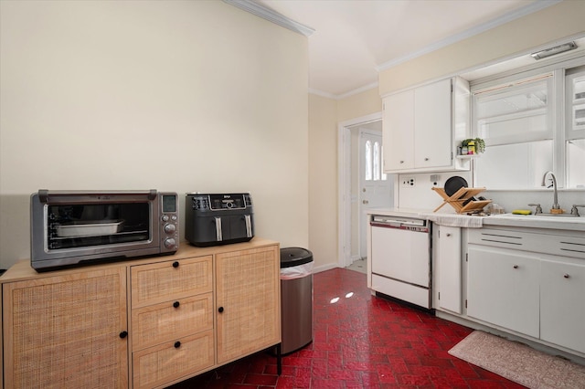 kitchen featuring brick floor, a sink, light countertops, dishwasher, and crown molding