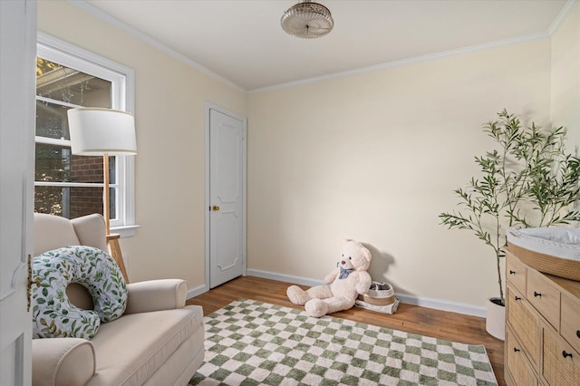 sitting room with baseboards, wood finished floors, and crown molding