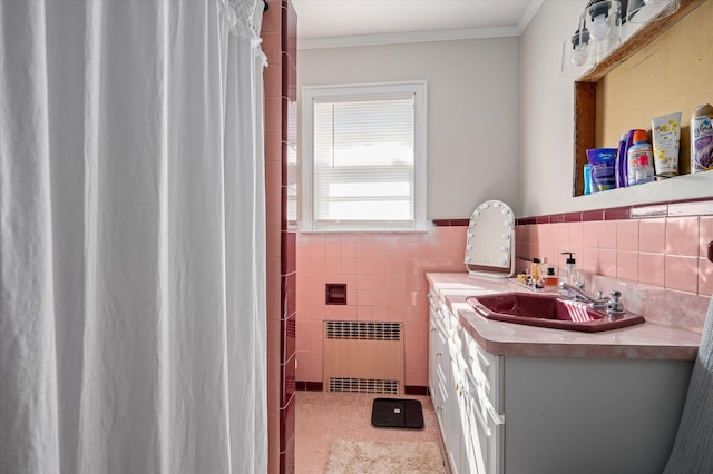 full bathroom with radiator heating unit, tile patterned flooring, crown molding, vanity, and tile walls