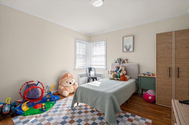 bedroom with radiator, crown molding, and wood finished floors