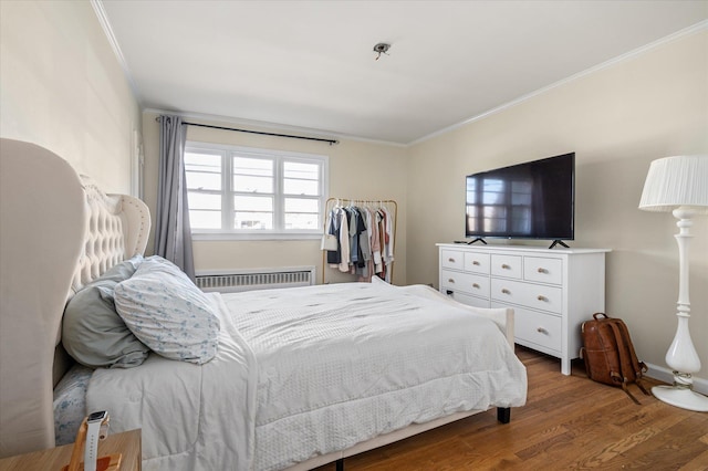 bedroom featuring ornamental molding, radiator heating unit, and wood finished floors