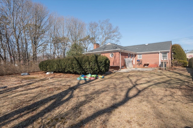 rear view of house featuring brick siding and a chimney