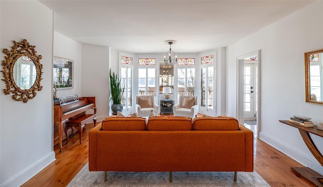 living room featuring a chandelier, light wood-style flooring, and baseboards