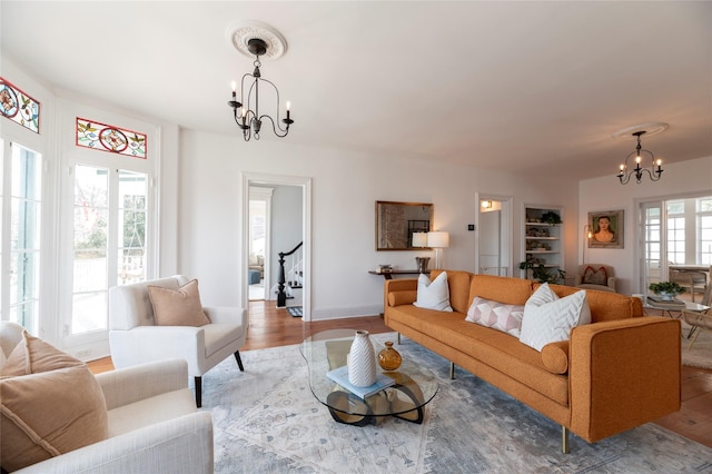 living area featuring a chandelier, stairs, baseboards, and wood finished floors