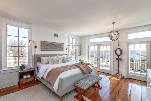 bedroom featuring a notable chandelier, visible vents, baseboards, access to exterior, and wood-type flooring