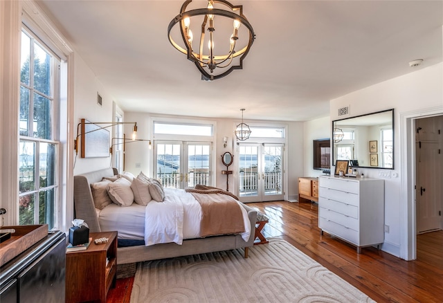 bedroom with access to exterior, visible vents, a notable chandelier, and hardwood / wood-style flooring