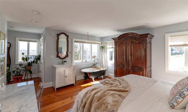 bedroom with light wood-type flooring, baseboards, and a sink