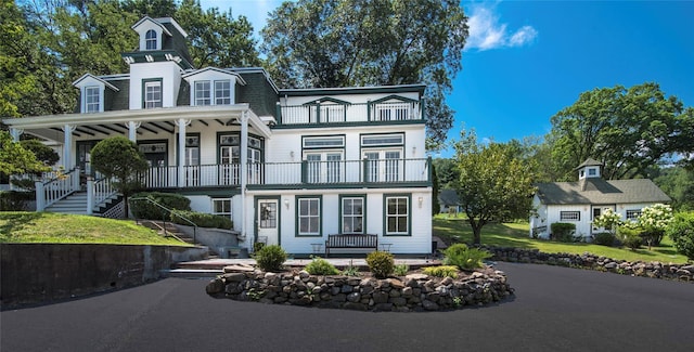 view of front of home featuring a balcony, mansard roof, stairway, and a porch