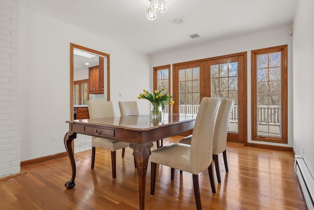 dining space with light wood finished floors, baseboard heating, visible vents, and baseboards