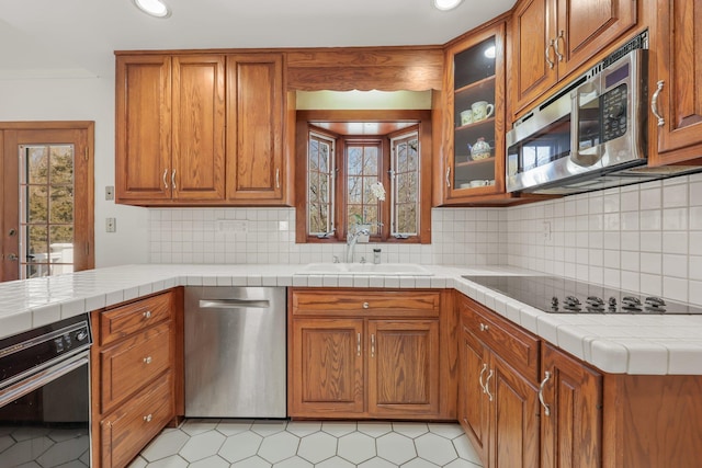 kitchen with plenty of natural light, appliances with stainless steel finishes, brown cabinetry, and a sink