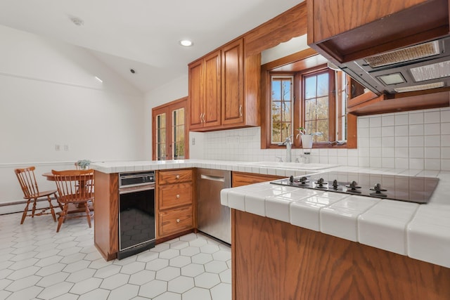 kitchen featuring tile countertops, a sink, brown cabinets, and dishwasher