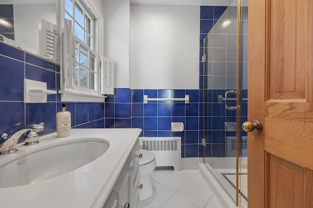 bathroom featuring tile walls, radiator, toilet, a shower stall, and tile patterned floors