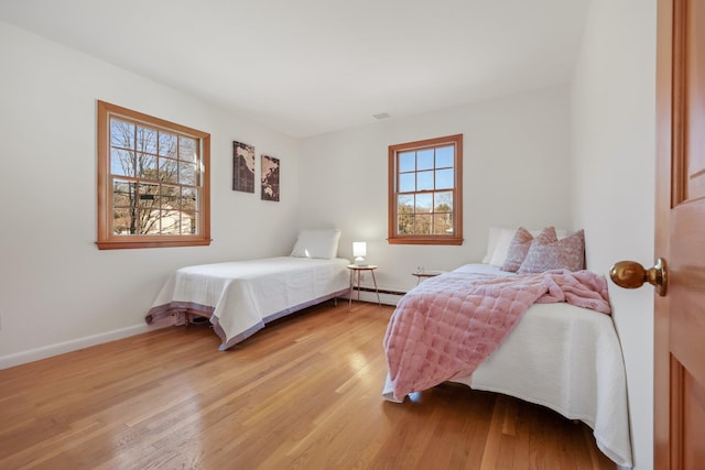 bedroom with visible vents, a baseboard radiator, light wood-style flooring, and baseboards