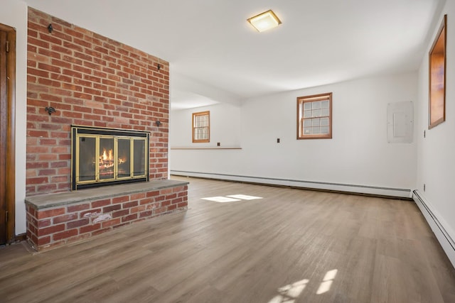 unfurnished living room with a baseboard heating unit, a brick fireplace, wood finished floors, and electric panel