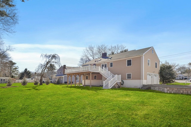 rear view of house with a garage, a lawn, a chimney, stairs, and a wooden deck