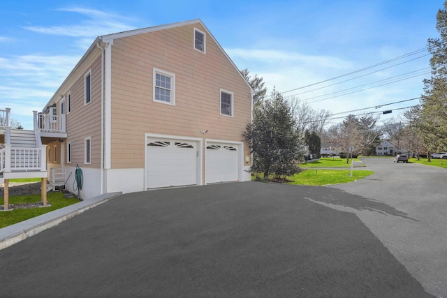 view of side of property with driveway, stairway, and an attached garage