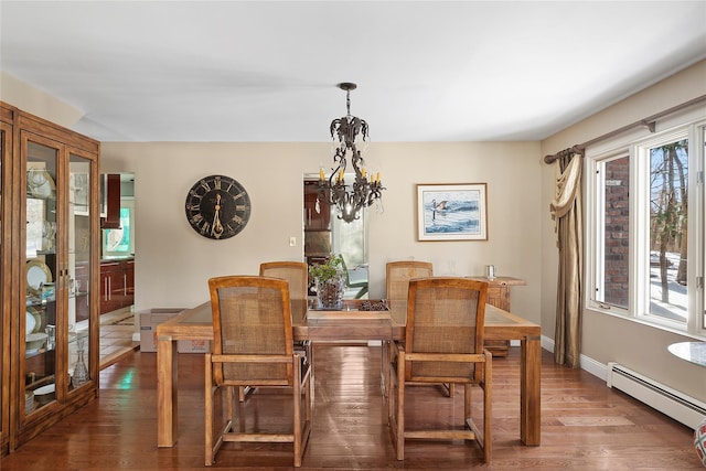 dining room featuring a baseboard heating unit, plenty of natural light, wood finished floors, and a chandelier