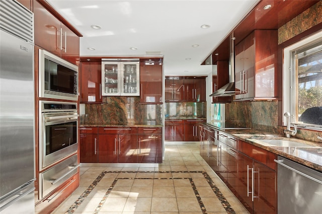 kitchen with reddish brown cabinets, a sink, decorative backsplash, and built in appliances