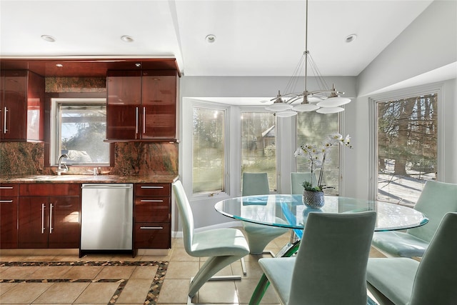 kitchen with reddish brown cabinets, light tile patterned floors, backsplash, a sink, and stainless steel dishwasher