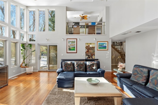 living room featuring light wood finished floors, baseboards, stairs, and visible vents