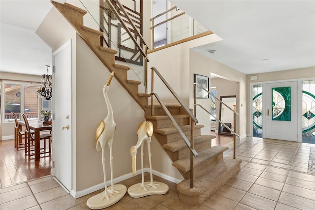 tiled foyer featuring a healthy amount of sunlight, baseboards, and stairs