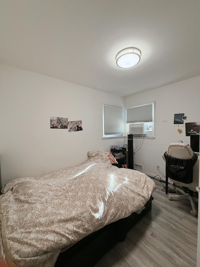 bedroom with cooling unit, wood finished floors, and visible vents