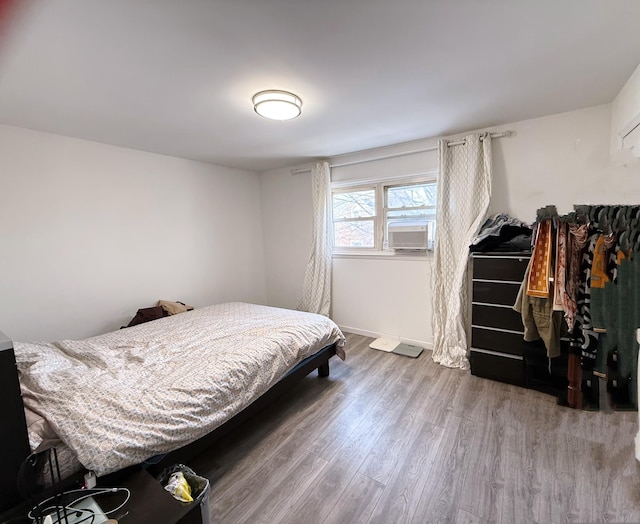 bedroom featuring baseboards, cooling unit, and wood finished floors