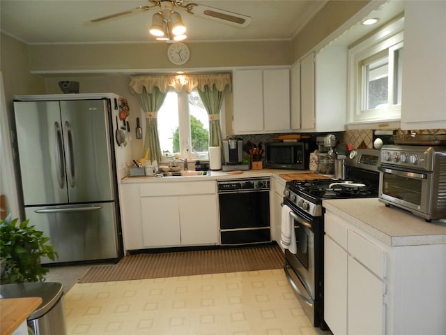 kitchen featuring a toaster, light countertops, appliances with stainless steel finishes, white cabinets, and a sink