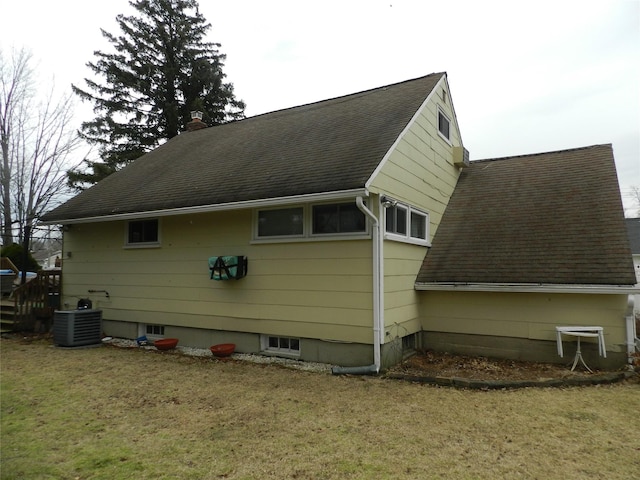 view of side of home featuring roof with shingles, a yard, and central air condition unit