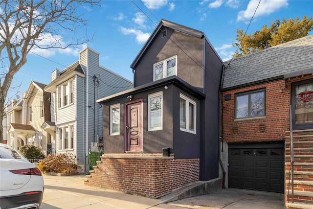 view of front facade featuring an attached garage, brick siding, concrete driveway, and stucco siding