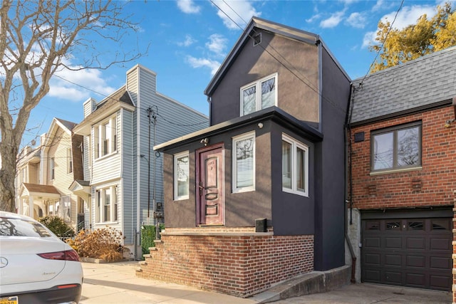 view of front of property with a garage, concrete driveway, brick siding, and stucco siding