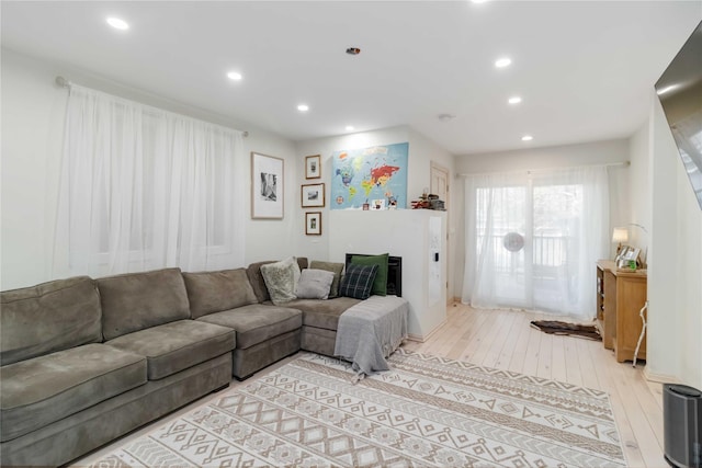 living room featuring light wood-style floors, recessed lighting, and a fireplace