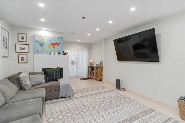 living area with a fireplace, wood finished floors, and recessed lighting