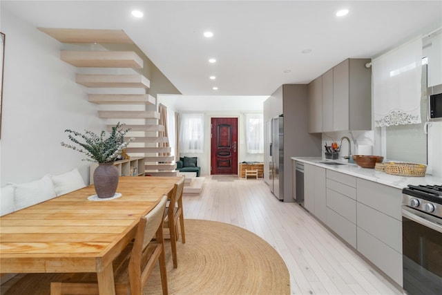 kitchen featuring modern cabinets, stainless steel appliances, gray cabinets, light countertops, and a sink